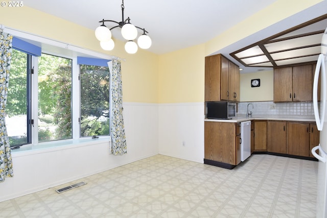 4296 SE Fieldcrest St, Milwaukie, OR 97222 - kitchen featuring light flooring, white dishwasher, stainless steel microwave, light countertops, and a chandelier