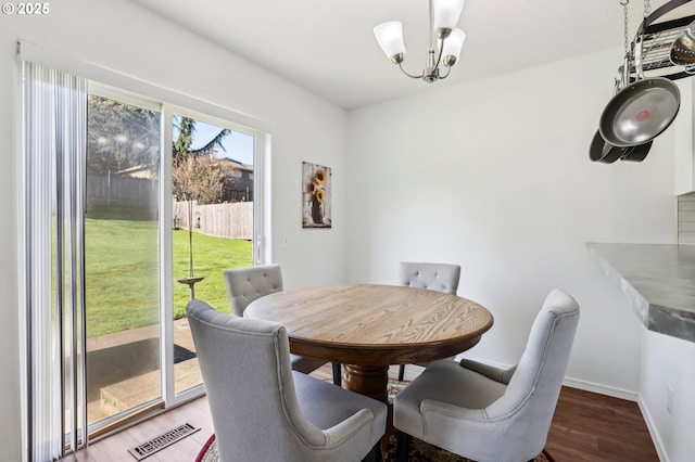 dining area featuring a chandelier, wood finished floors, visible vents, and baseboards