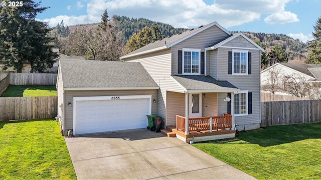 traditional-style home featuring an attached garage, fence, a front lawn, and concrete driveway