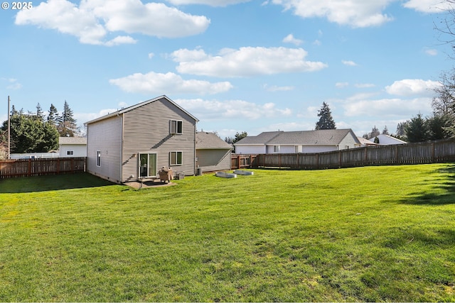 rear view of property featuring a fenced backyard and a lawn