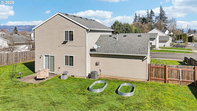 back of house with roof with shingles, a patio, a yard, central AC unit, and fence