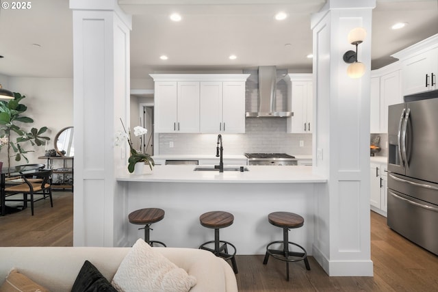 kitchen with white cabinets, wall chimney exhaust hood, light countertops, and stainless steel fridge with ice dispenser