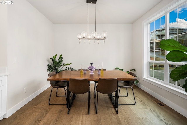 dining room featuring an inviting chandelier, visible vents, baseboards, and wood finished floors