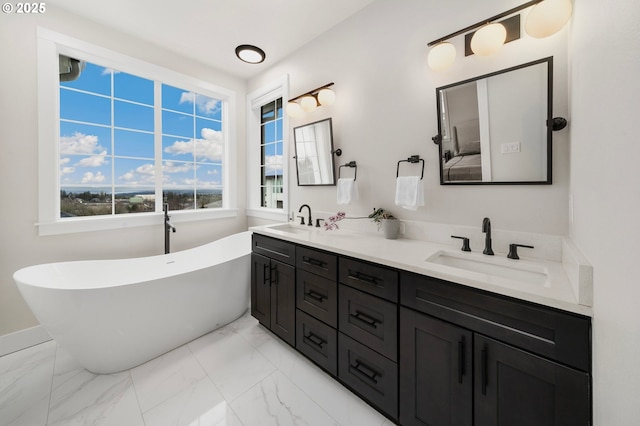 full bath featuring marble finish floor, double vanity, a soaking tub, and a sink