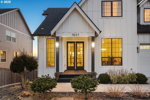 view of exterior entry featuring fence, board and batten siding, and roof with shingles