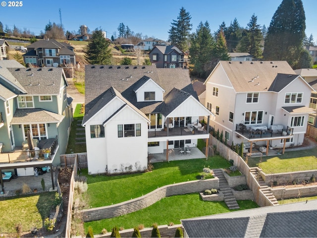 rear view of house with board and batten siding, a residential view, a fenced backyard, and roof with shingles