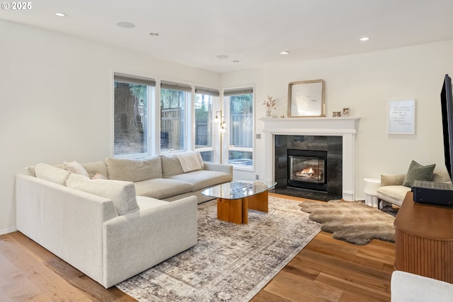 living room featuring a tiled fireplace, recessed lighting, and wood finished floors