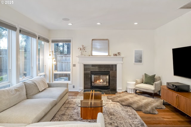 living area with recessed lighting, visible vents, wood finished floors, and a tiled fireplace