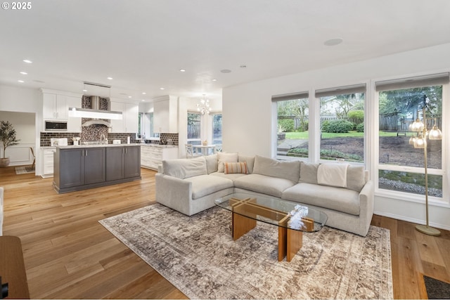 living room featuring recessed lighting, light wood-type flooring, baseboards, and an inviting chandelier