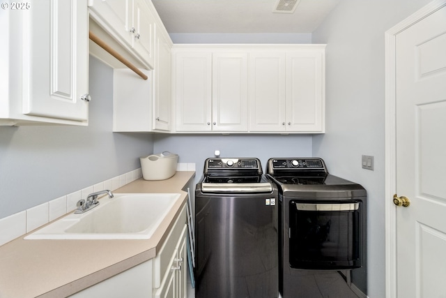 washroom with visible vents, cabinet space, washer and dryer, and a sink