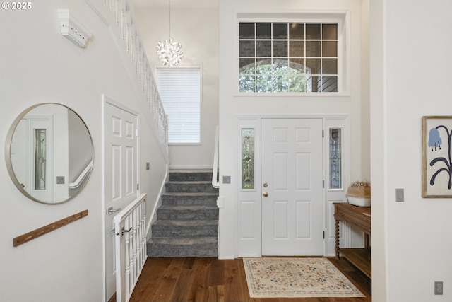 entryway featuring stairway, a high ceiling, an inviting chandelier, and dark wood-style flooring