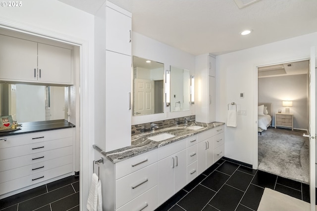 ensuite bathroom featuring tile patterned floors, double vanity, and a sink