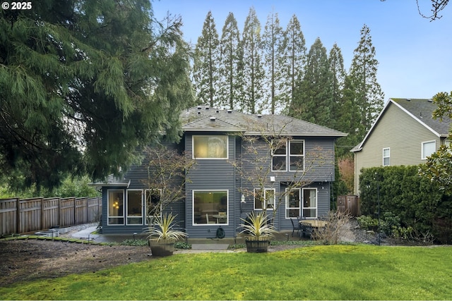 rear view of property featuring a yard, a patio area, and fence