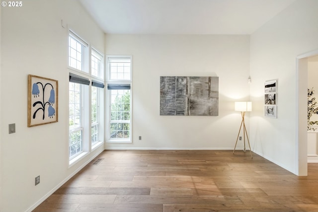 spare room with visible vents, baseboards, and wood finished floors