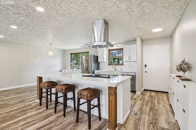 1213 NW Westridge St, Vancouver, WA 98665 - kitchen featuring appliances with stainless steel finishes, island exhaust hood, light wood-type flooring, a breakfast bar, and recessed lighting
