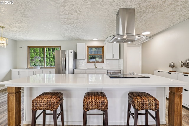 1213 NW Westridge St, Vancouver, WA 98665 - kitchen with freestanding refrigerator, island range hood, black electric stovetop, a breakfast bar, and recessed lighting