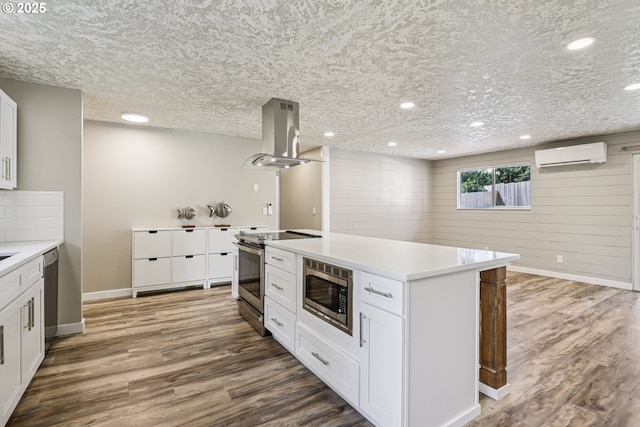 1213 NW Westridge St, Vancouver, WA 98665 - kitchen featuring stainless steel appliances, island range hood, a wall mounted AC, light countertops, and white cabinetry
