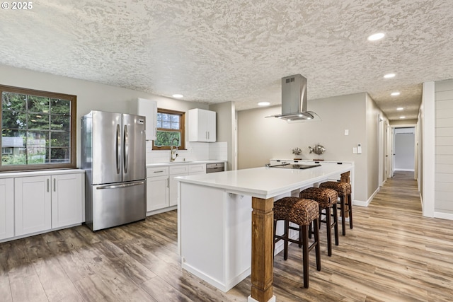 1213 NW Westridge St, Vancouver, WA 98665 - kitchen featuring freestanding refrigerator, island exhaust hood, light wood-type flooring, a breakfast bar, and recessed lighting