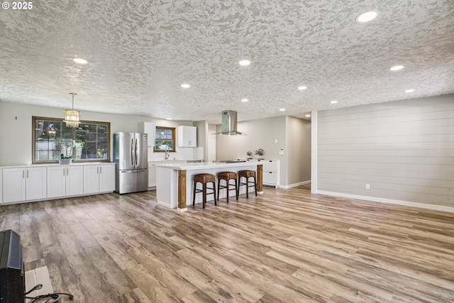 1213 NW Westridge St, Vancouver, WA 98665 - kitchen featuring freestanding refrigerator, range hood, a kitchen bar, a center island, and light wood-type flooring