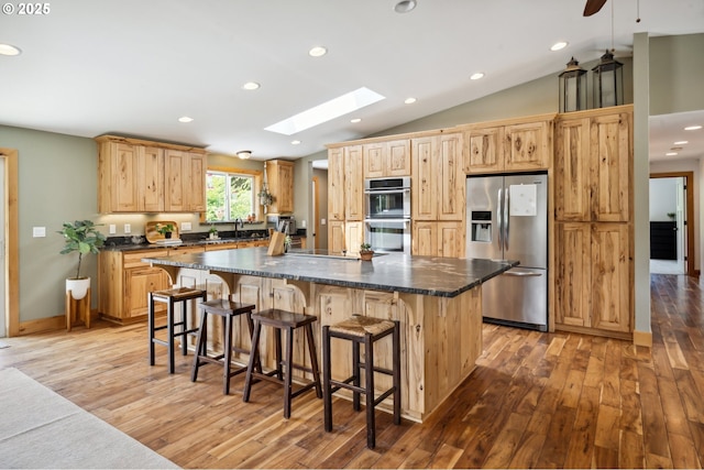 40774 SE Trubel Rd, Sandy, OR 97055 - kitchen featuring appliances with stainless steel finishes, light wood finished floors, a skylight, vaulted ceiling, and a spacious island