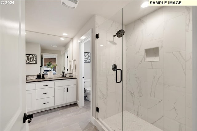 bathroom with vanity, a shower with door, and toilet