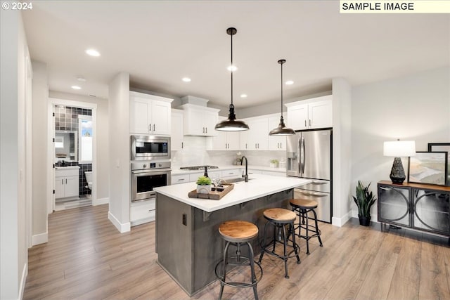 kitchen featuring white cabinetry, sink, a center island with sink, and appliances with stainless steel finishes