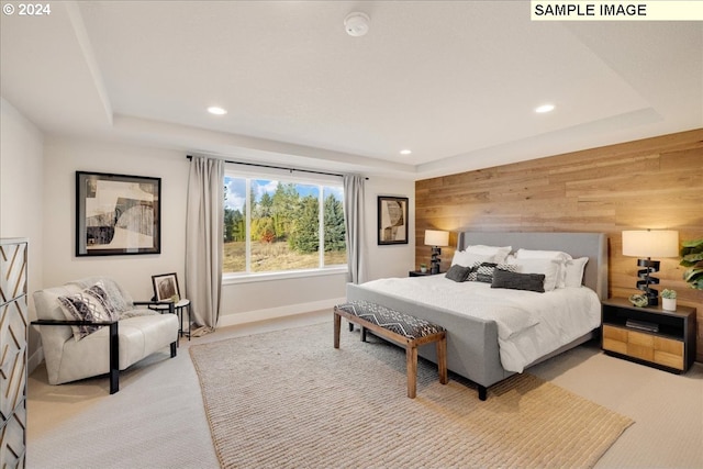 bedroom with a tray ceiling, wooden walls, and light colored carpet