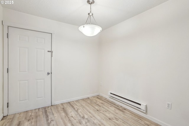 unfurnished room with light hardwood / wood-style floors, a textured ceiling, and a baseboard heating unit