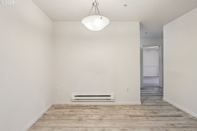 unfurnished room with baseboard heating and light hardwood / wood-style floors