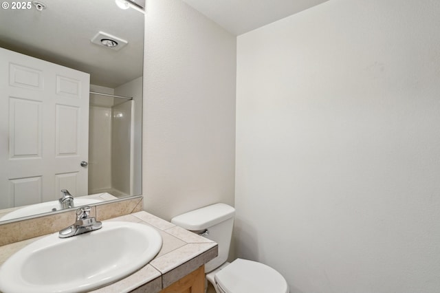 bathroom featuring vanity, a shower, and toilet