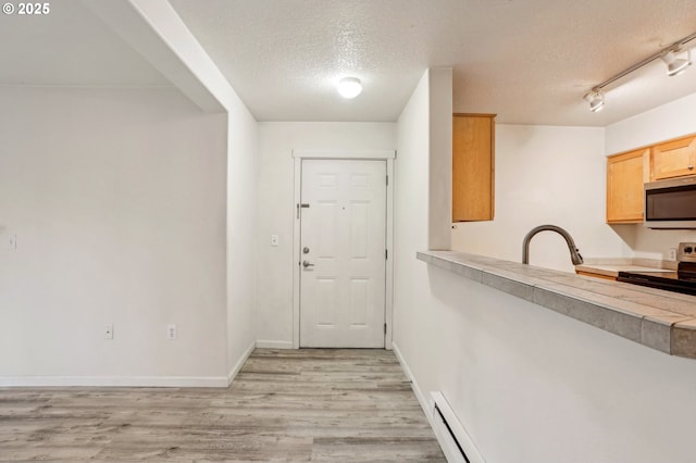 kitchen featuring sink, light hardwood / wood-style flooring, a textured ceiling, light brown cabinets, and stainless steel appliances