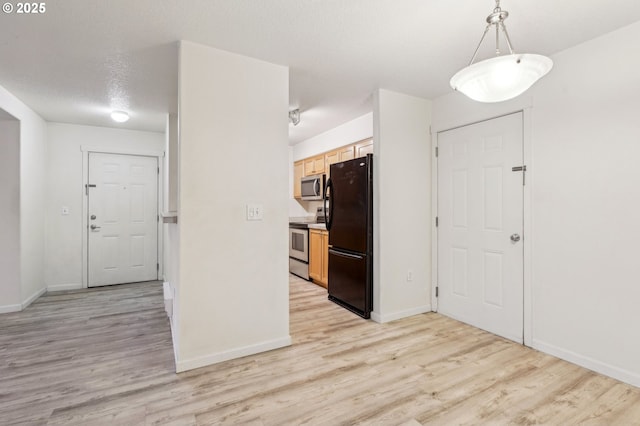 kitchen featuring stainless steel appliances, hanging light fixtures, light wood-type flooring, and light brown cabinetry