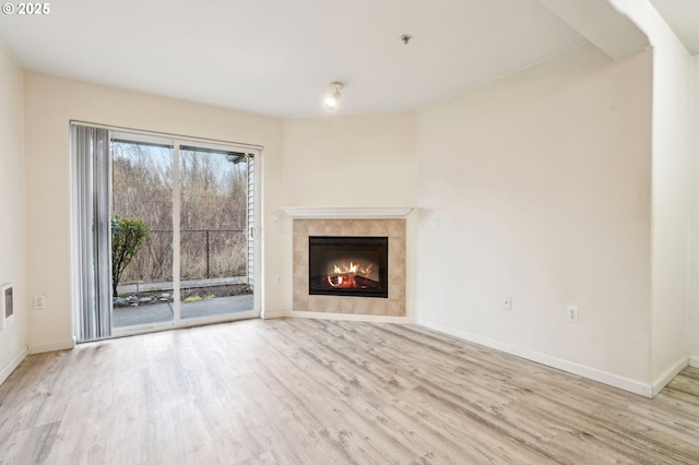 unfurnished living room with light hardwood / wood-style flooring and a tile fireplace