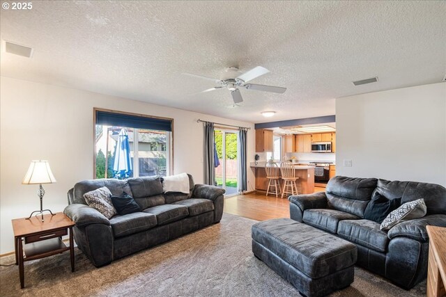 living room featuring a textured ceiling, visible vents, and ceiling fan