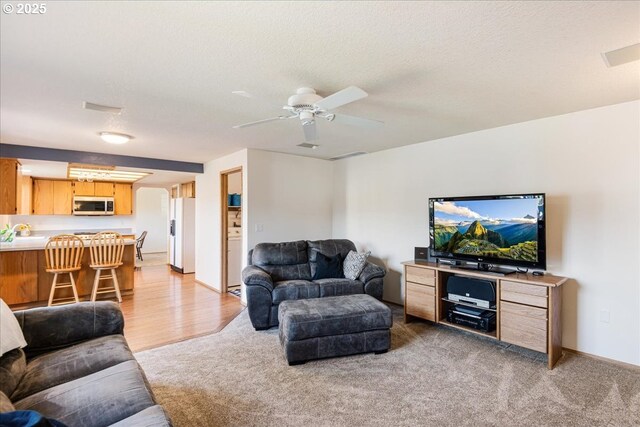 living room featuring a ceiling fan, baseboards, and light carpet