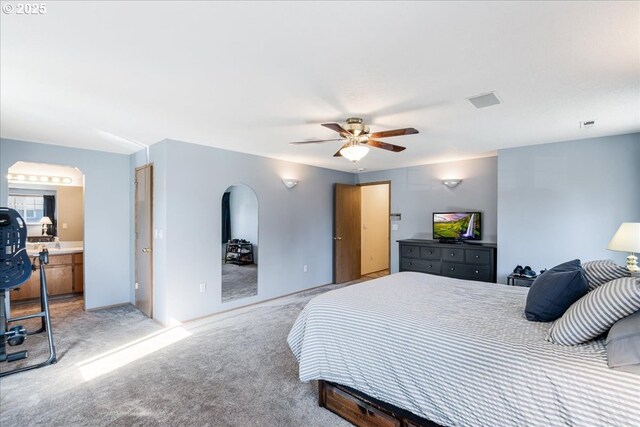bedroom featuring visible vents, arched walkways, a ceiling fan, and light carpet