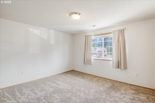 carpeted empty room featuring a textured ceiling, visible vents, and baseboards