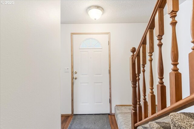 doorway featuring a textured ceiling, wood finished floors, and stairway
