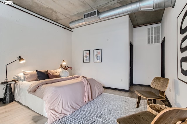 bedroom with visible vents, baseboards, and wood finished floors