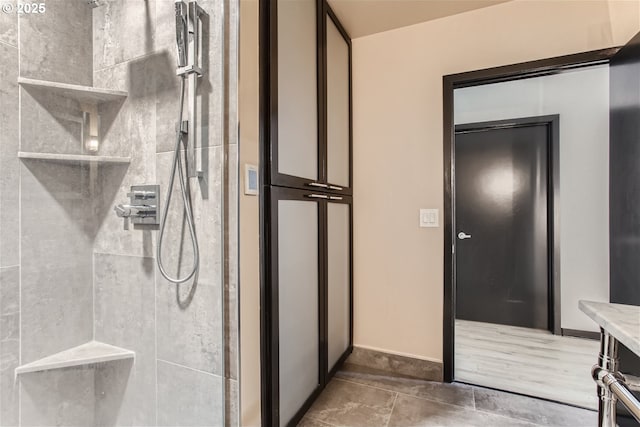 bathroom with baseboards and a tile shower