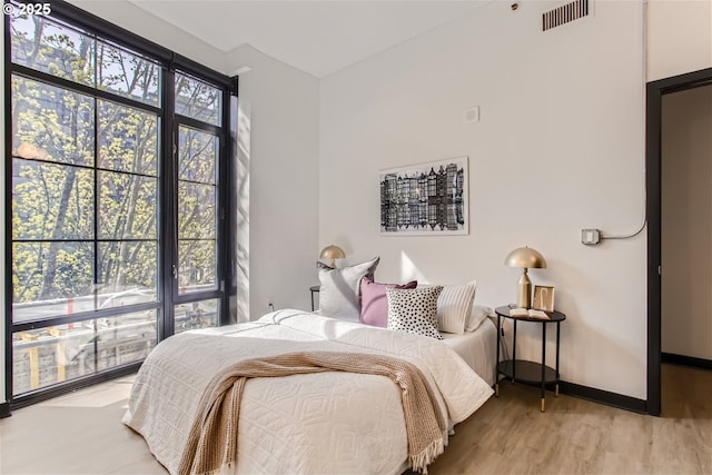 bedroom with baseboards, visible vents, and light wood finished floors