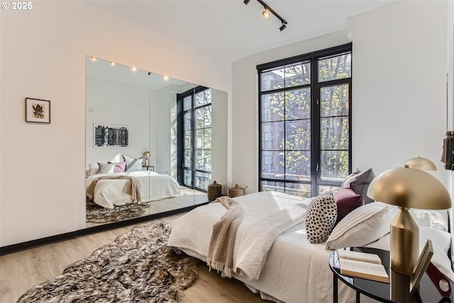 bedroom featuring track lighting and light wood-type flooring