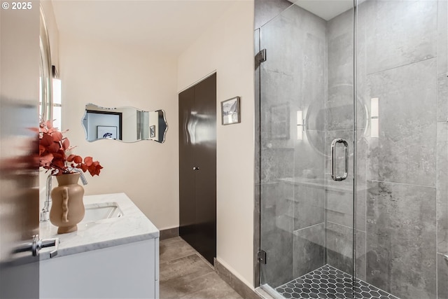 full bathroom with baseboards, a shower stall, and vanity