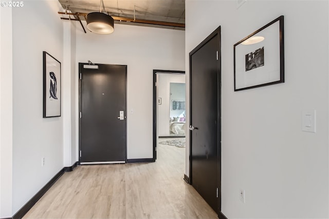 corridor featuring baseboards and light wood finished floors