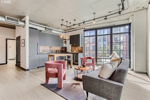 living room with visible vents, baseboards, wine cooler, and light wood-type flooring