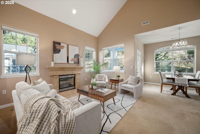 living room featuring high vaulted ceiling, plenty of natural light, light carpet, and a chandelier