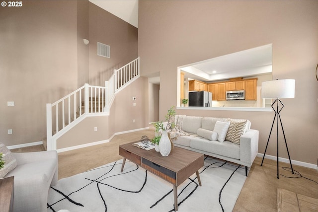 carpeted living room with a high ceiling and a tray ceiling