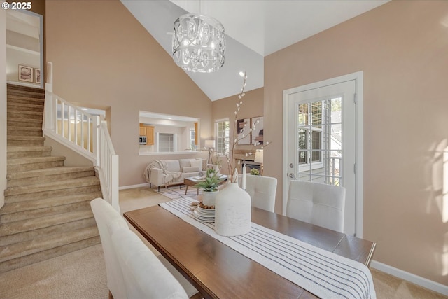 dining area featuring high vaulted ceiling, light carpet, and a chandelier