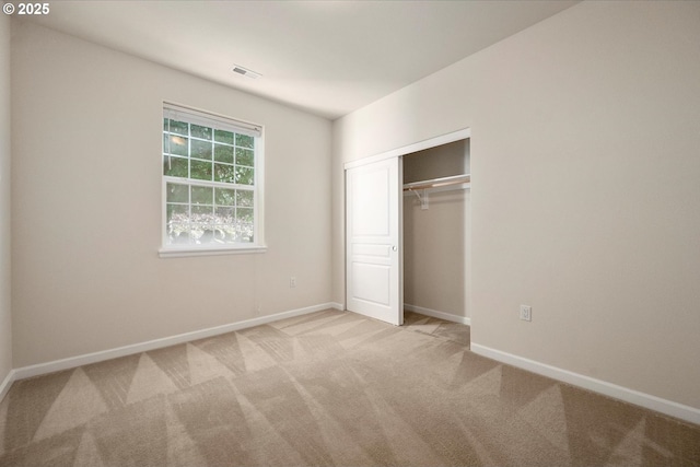 unfurnished bedroom featuring light colored carpet and a closet