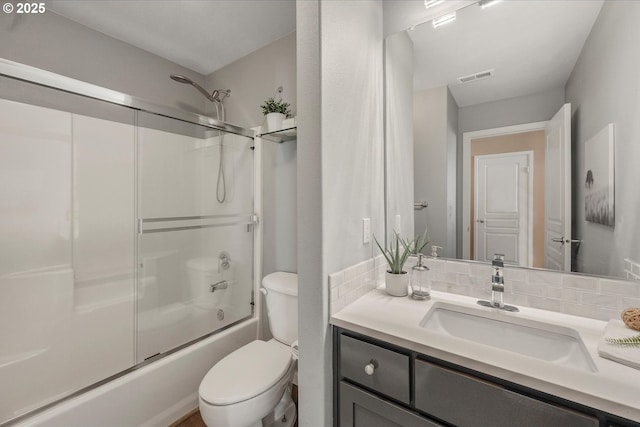 full bathroom with combined bath / shower with glass door, vanity, backsplash, and toilet